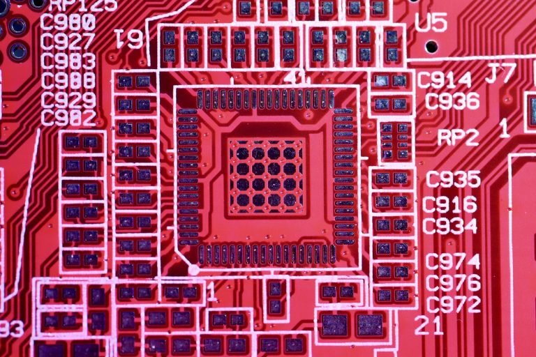 Top view of contemporary bright red printed board with electric circuits and various numbers with letters of modern electronic device